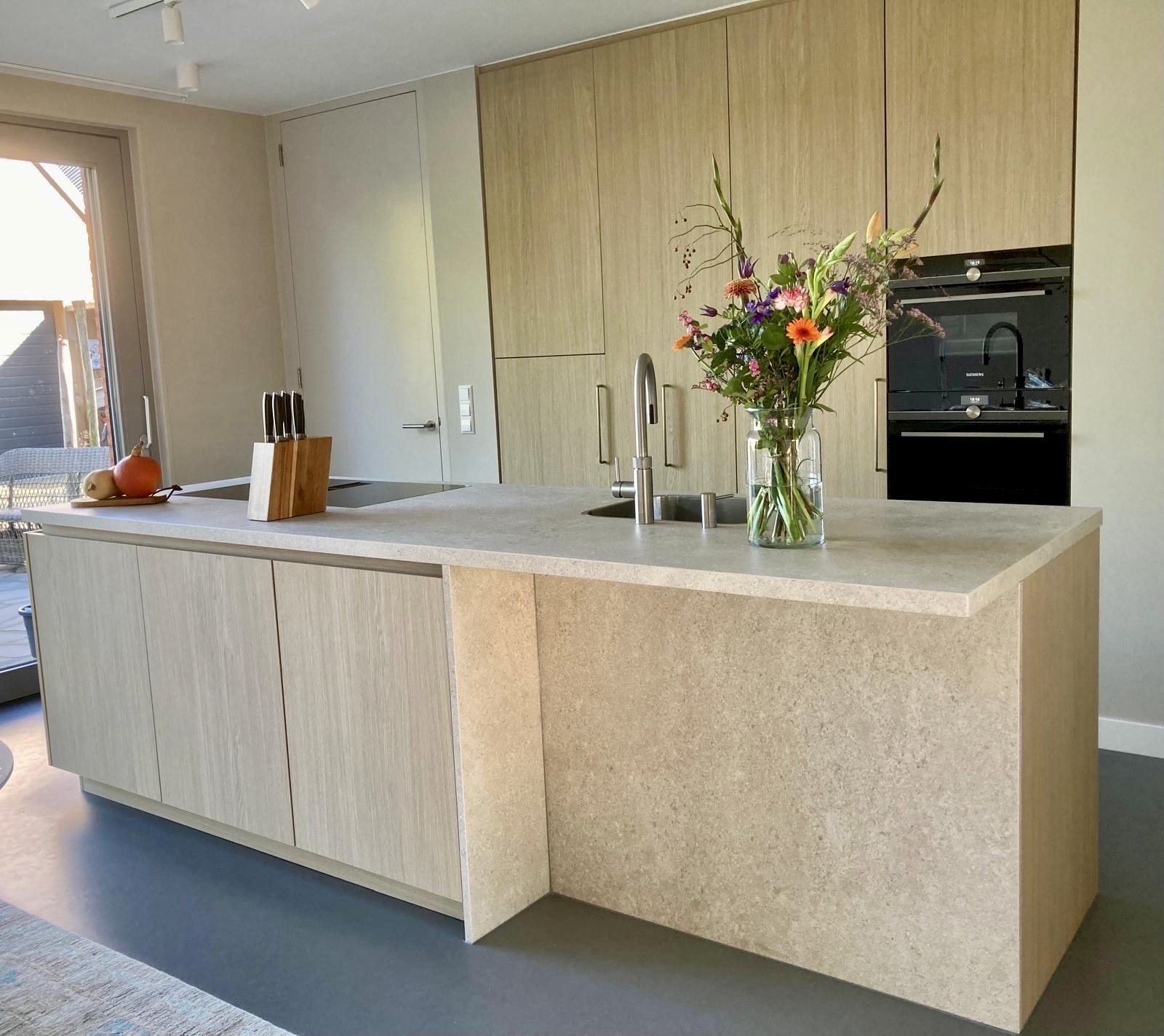 Moderne keuken met houten kastenwand en eiland in steenlook afwerking