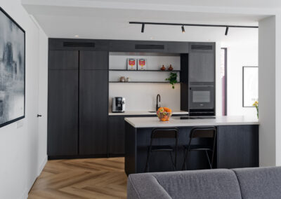 Moderne open keuken met kookeiland en donkere kastenwand.