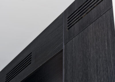 Detail van donkere keukenkast met ventilatierooster en strakke afwerking.