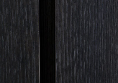 Detail van donkere houten wand met verticale structuur en zwarte voeg.