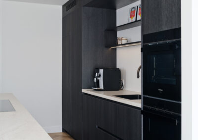 Moderne keuken met donkere kastenwand en ingebouwde oven.