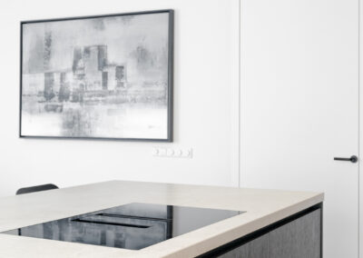 Moderne keuken met kookeiland, inductiekookplaat en strakke witte wanden.