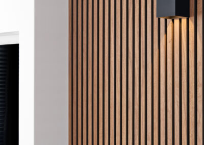 Houten lattenwand met zwarte wandlamp in modern interieur.