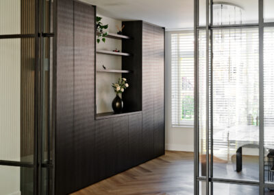 Donkere houten wand met nis en zicht door glazen deur.