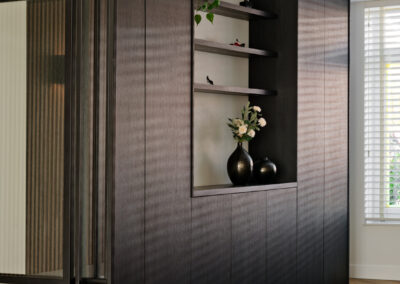 Donkere houten wand met nis en zicht door glazen deur.