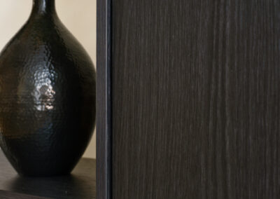 Donkere houten wand met nis en decoratieve vaas.
