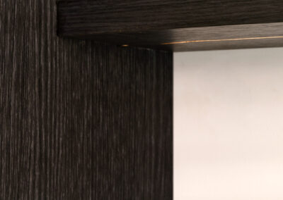 Donkere houten wand met strak afgewerkte plank in modern interieur.