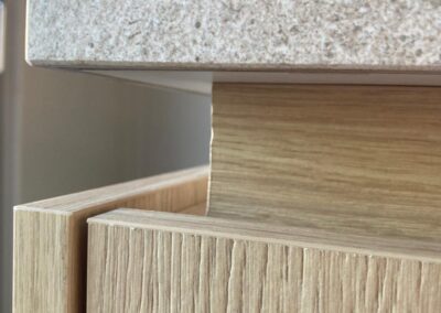 Detail van keuken met houten lade en overstekend stenen werkblad