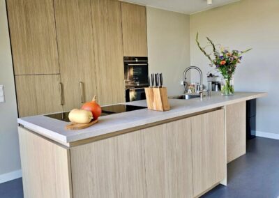 Moderne houten keuken met kookeiland, geïntegreerde apparatuur en lichte werkblad