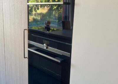 Detail van houten keukeneiland met greeploze lades en licht werkblad