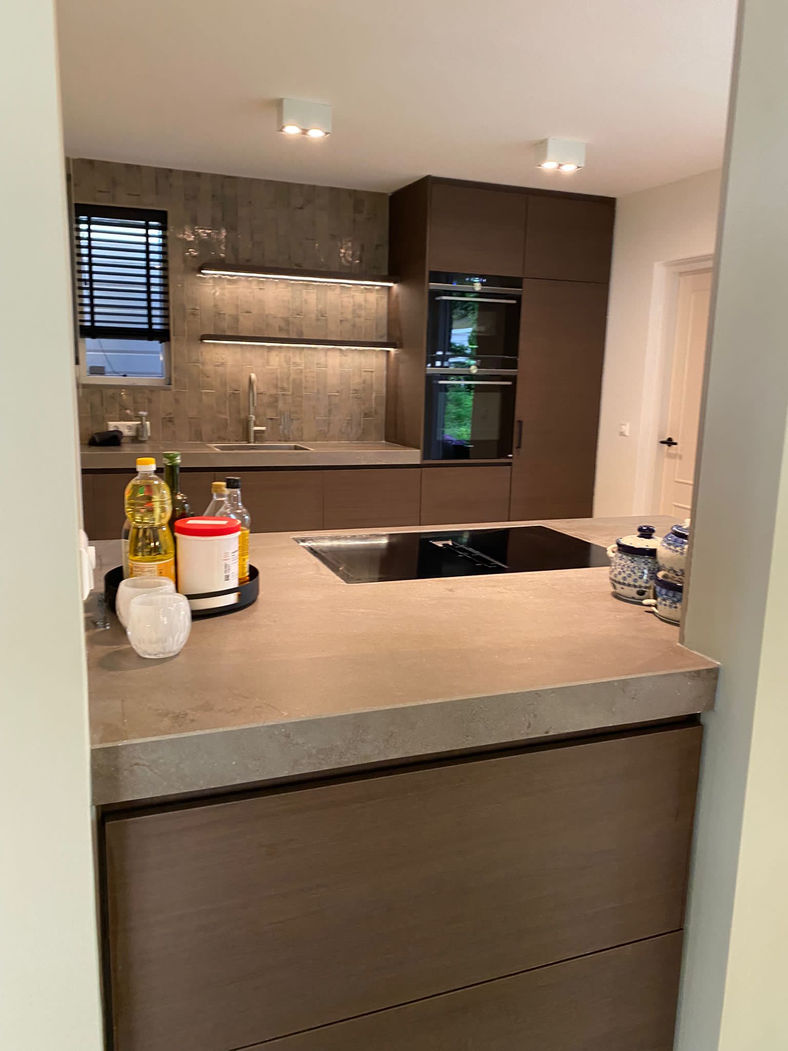 Moderne keuken met eiland en wijnkoelkast Keuken met kookeiland, houten kasten en ingebouwde wijnkoelkast.